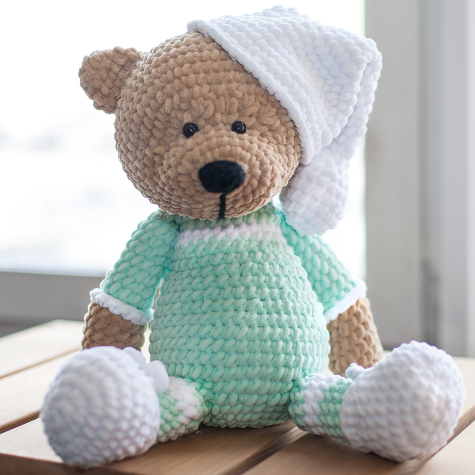 Handmade amigurumi teddy bear on wooden table